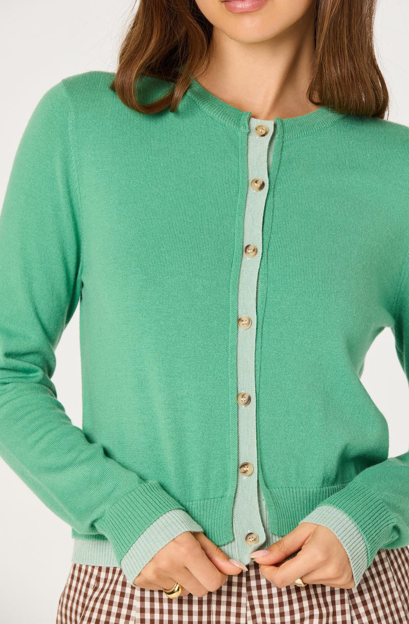 Green cardigan with cream buttons and light green accents on cuffs and front opening.