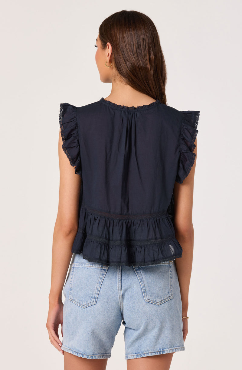 Woman wearing a navy blue sleeveless top with ruffled sleeves and a peplum hem.