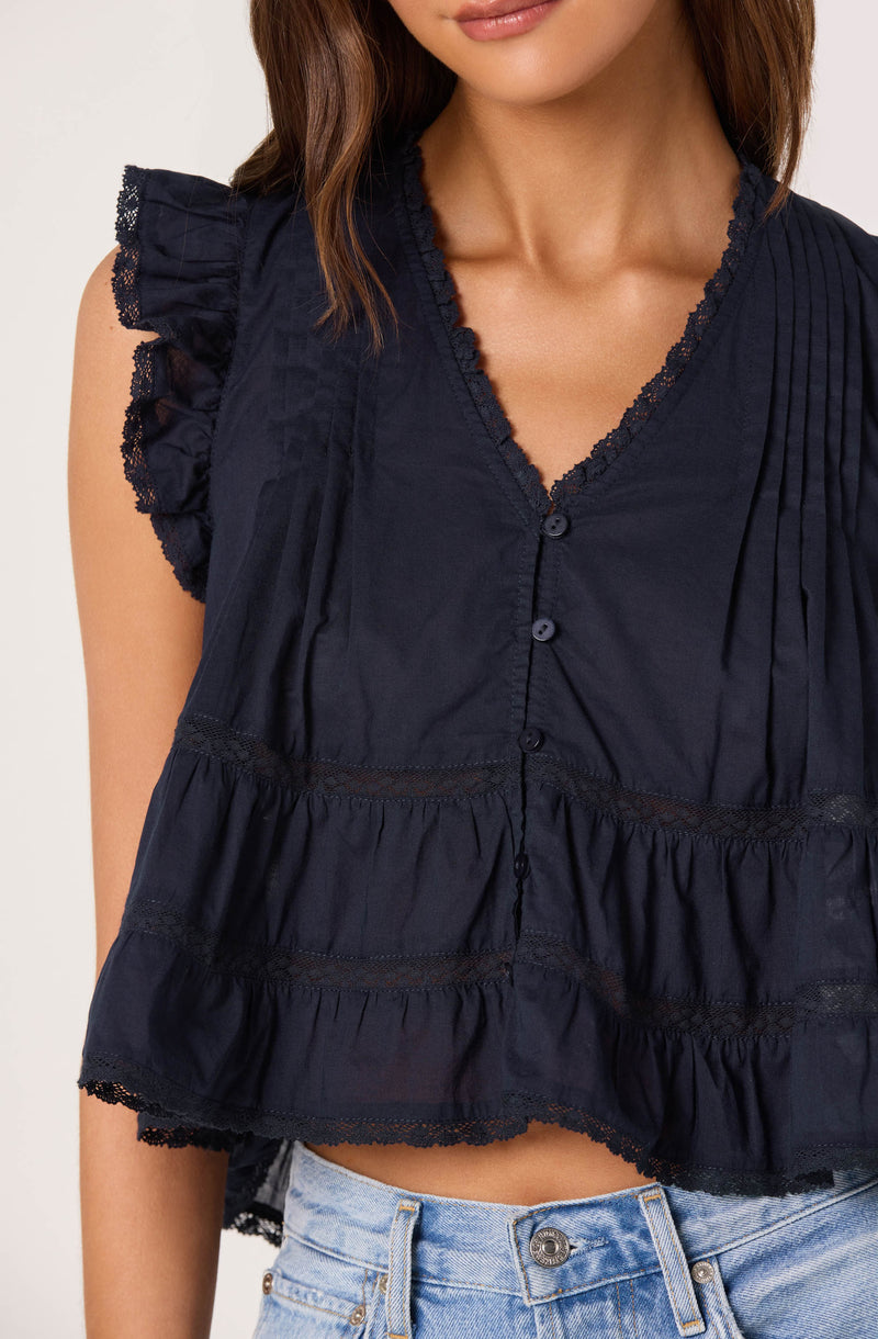 Navy sleeveless top with ruffled shoulder detail, lace trim, and tiered, gathered fabric.