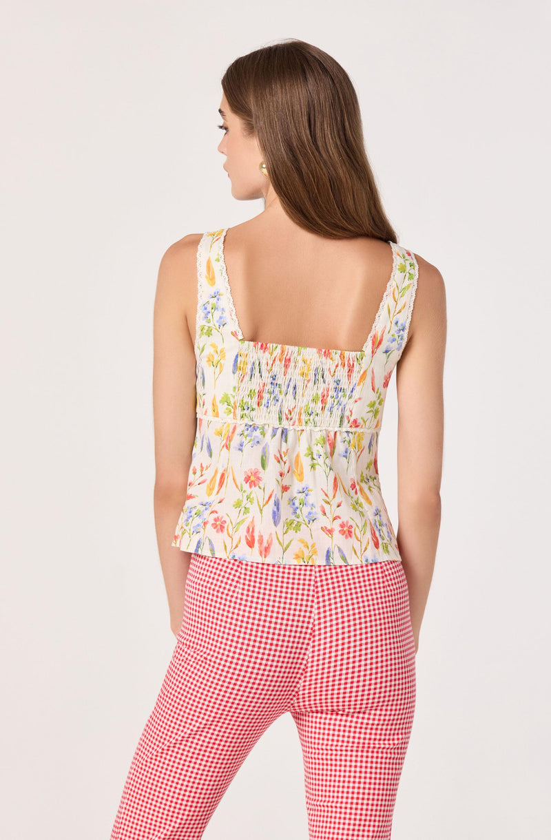 Sleeveless floral top with smocked bodice, paired with red and white gingham pants.