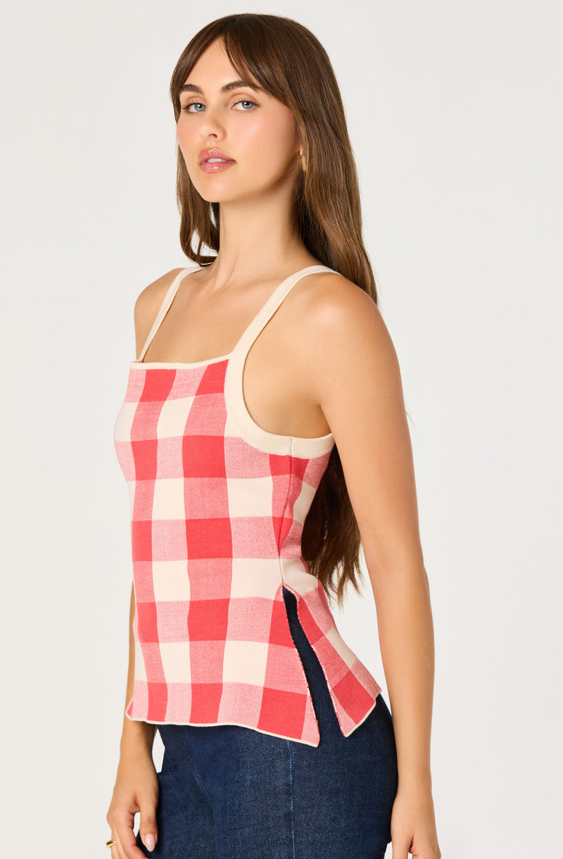 Woman wearing a sleeveless red and white checkered top with beige straps and side slits.