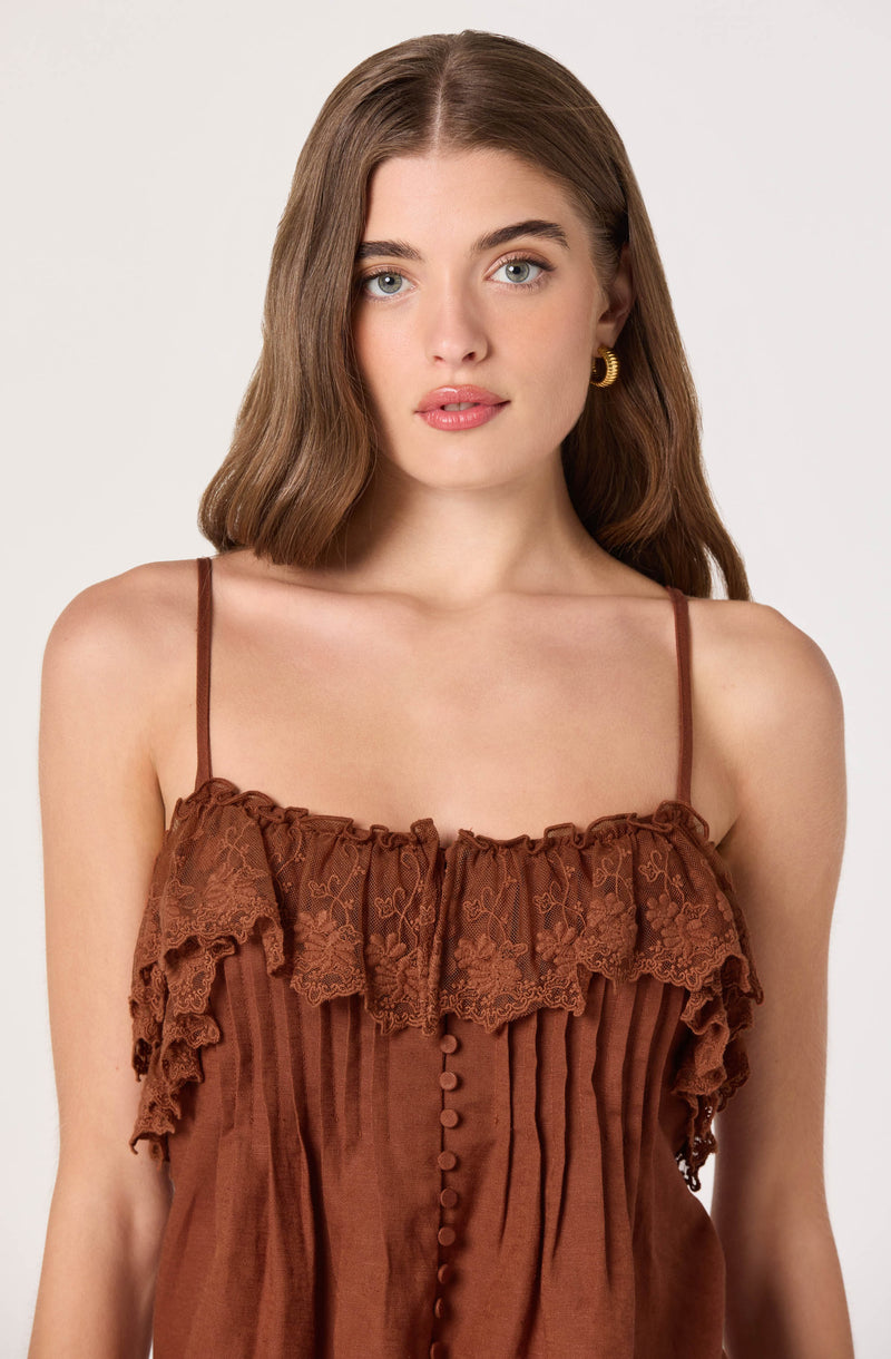 Girl in a brown spaghetti strap top with ruffles and lace details.