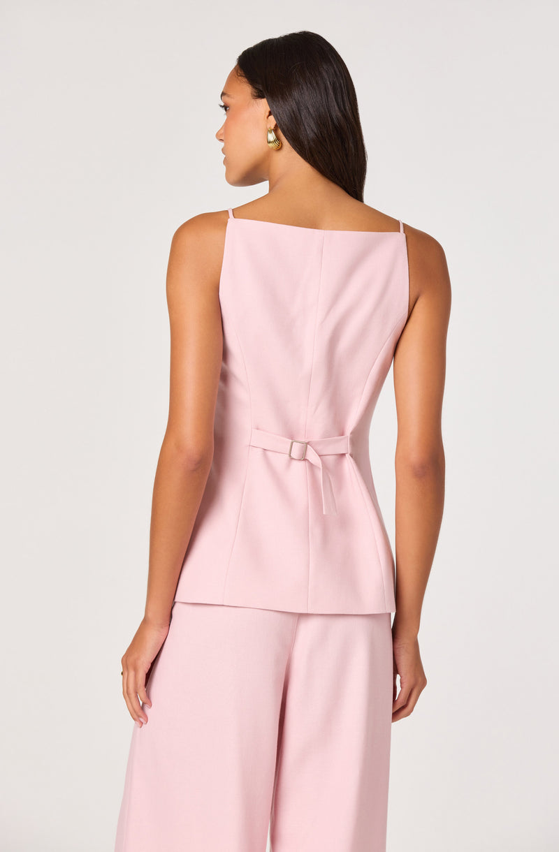 Woman in pink sleeveless top and wide-leg pants, looking to the side.