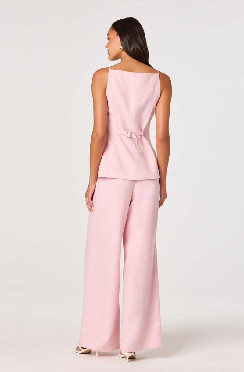 Woman in a light pink sleeveless top with thin straps and wide-leg pink pants.