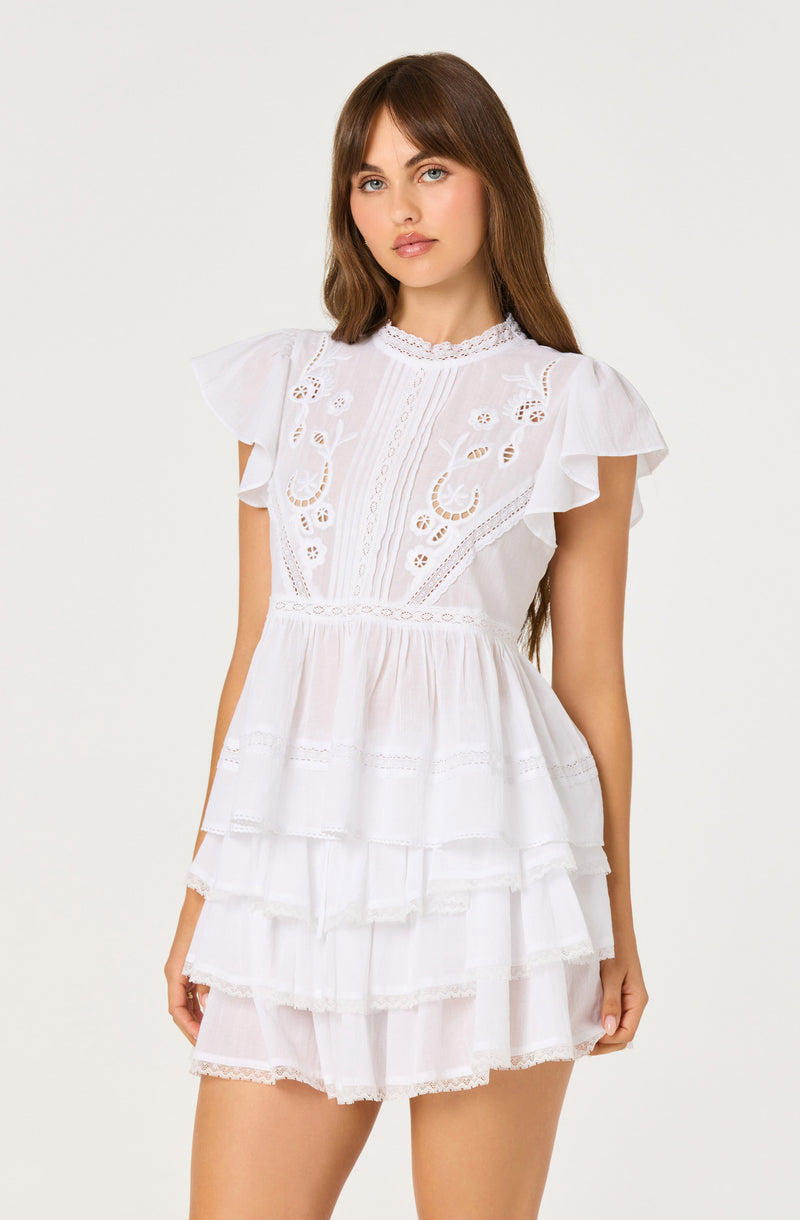 White dress with embroidered bodice, ruffled sleeves, and tiered skirt.