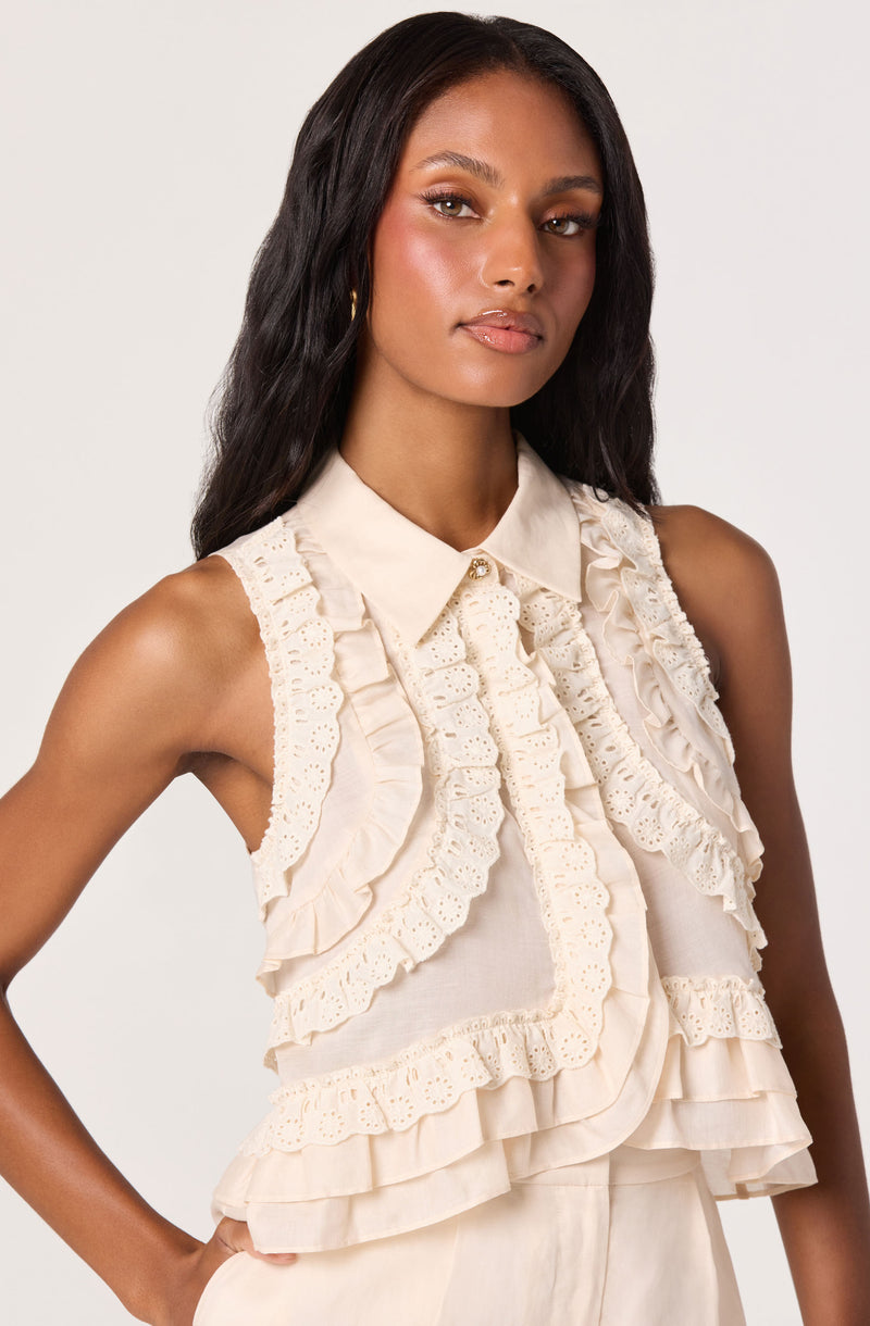 Cream sleeveless blouse with ruffles and eyelet lace detailing.