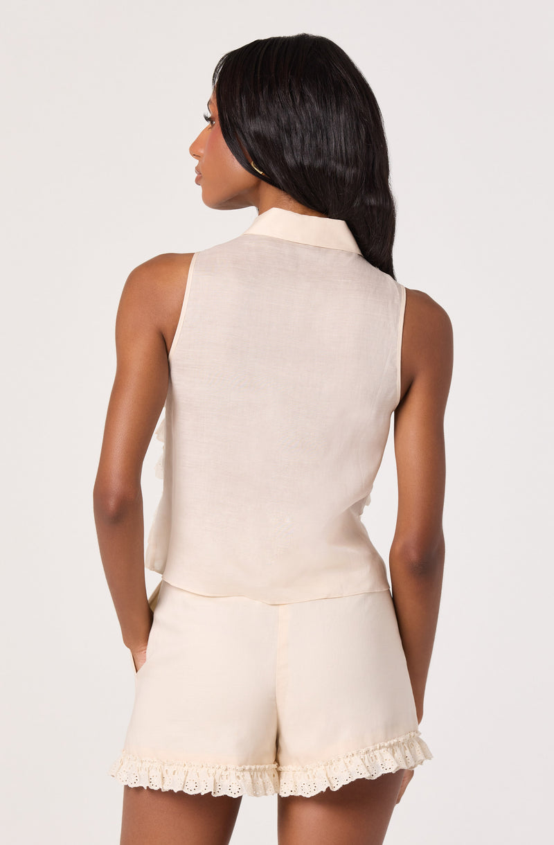 Woman wearing sleeveless cream blouse and matching cream shorts with lace trim.