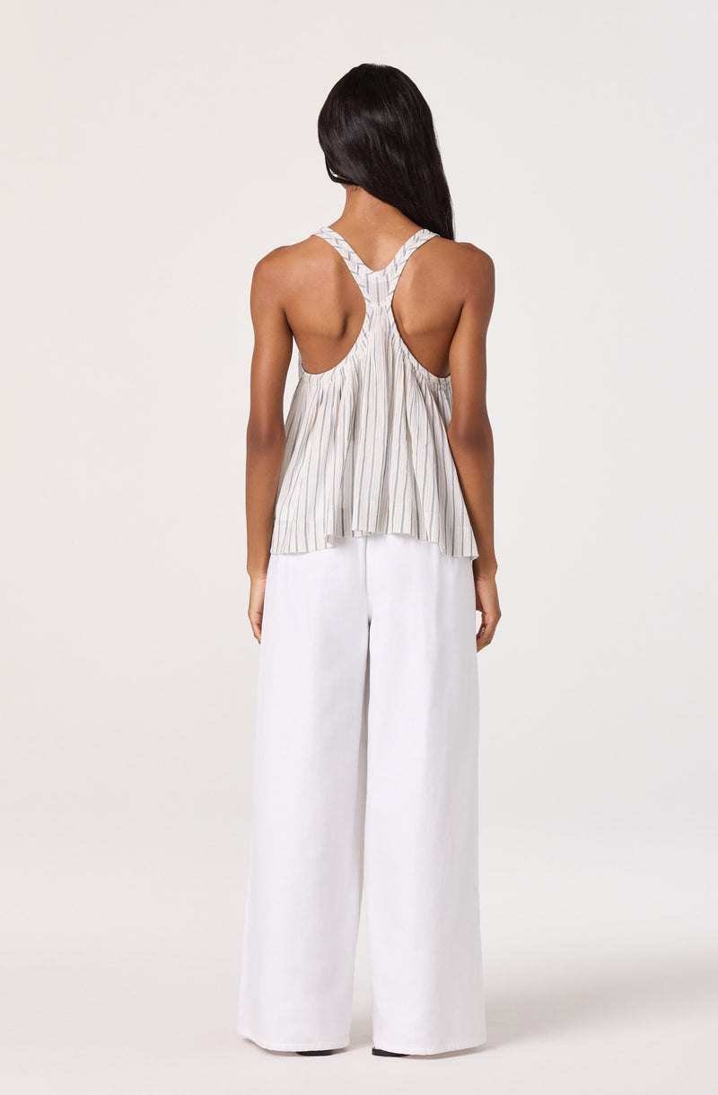 Woman wears a striped sleeveless top with racerback and wide-leg white pants.