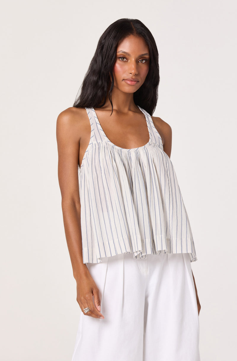 Woman wearing a sleeveless, striped, loose-fitting top with vertical lines and a round neckline.