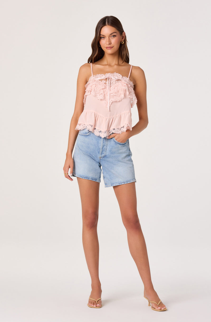 Pink ruffled camisole top with lace details and thin straps, paired with light blue denim shorts.