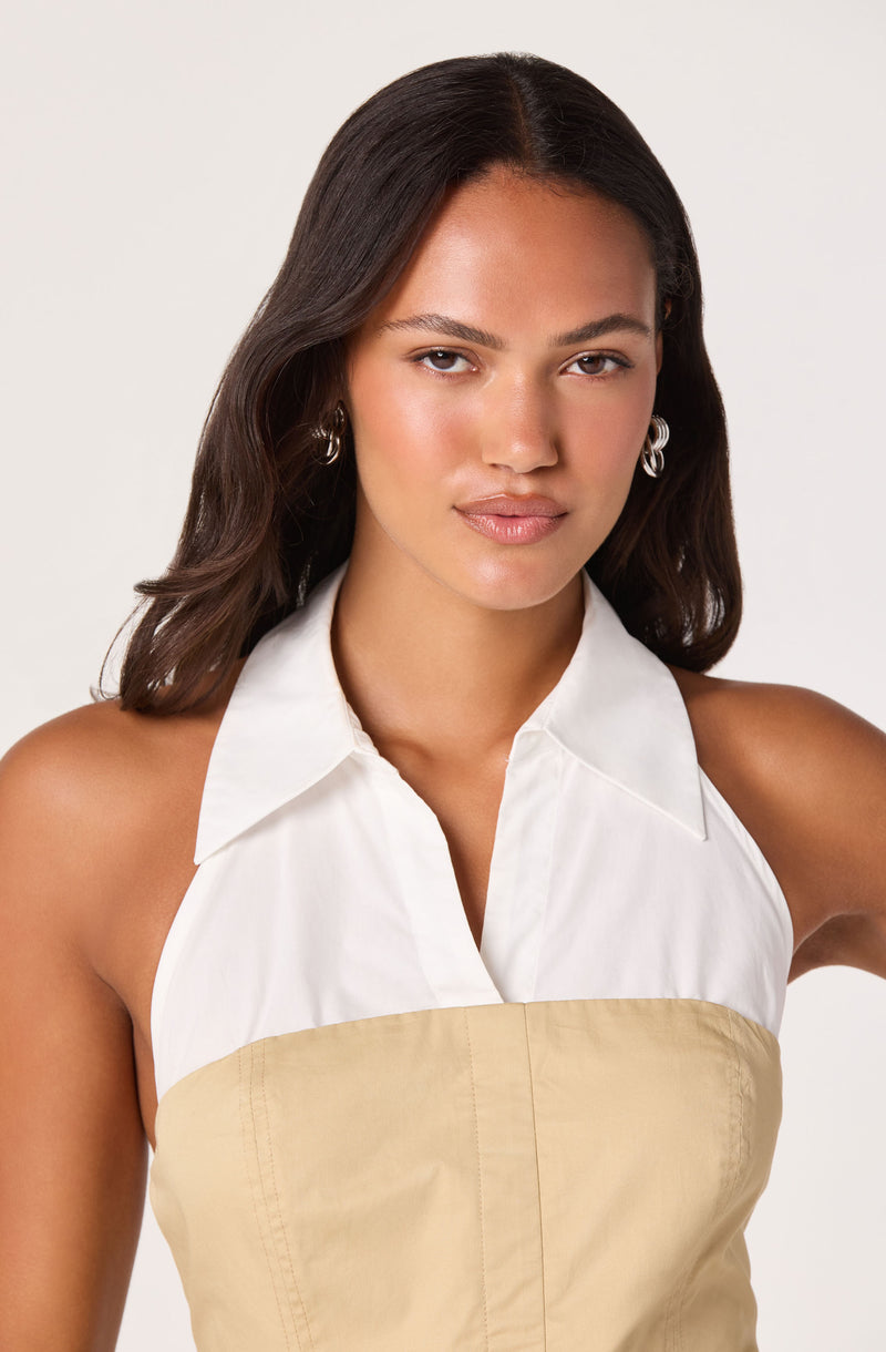 Woman wearing a sleeveless white and beige collared dress.