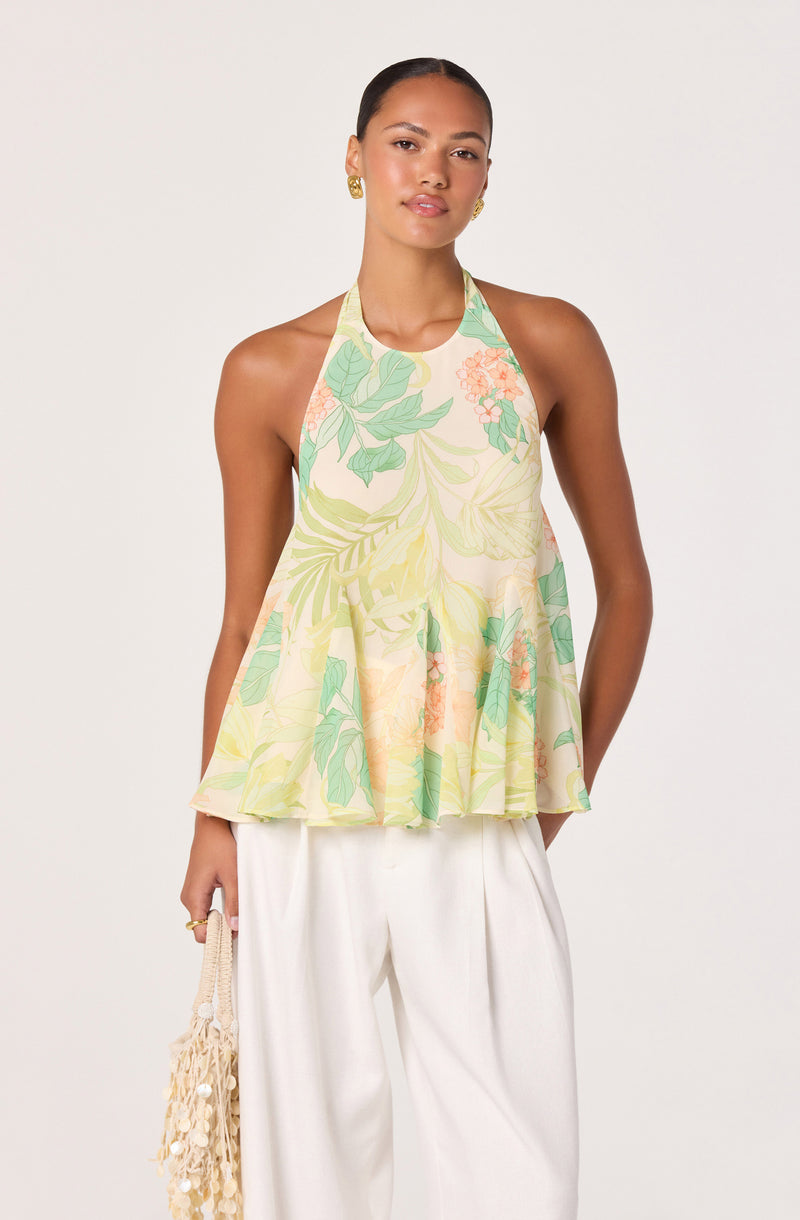 Woman wearing a sleeveless, flowy halter top with a pastel floral pattern and wide-leg white pants.