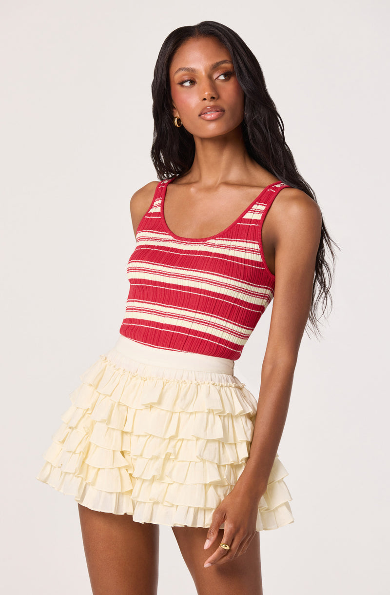 Woman wearing a red and white striped sleeveless top and a cream layered ruffle skirt.