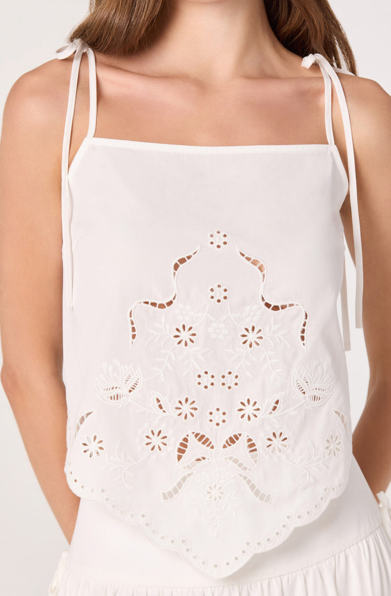 White eyelet sleeveless top with floral embroidery and scalloped hem.