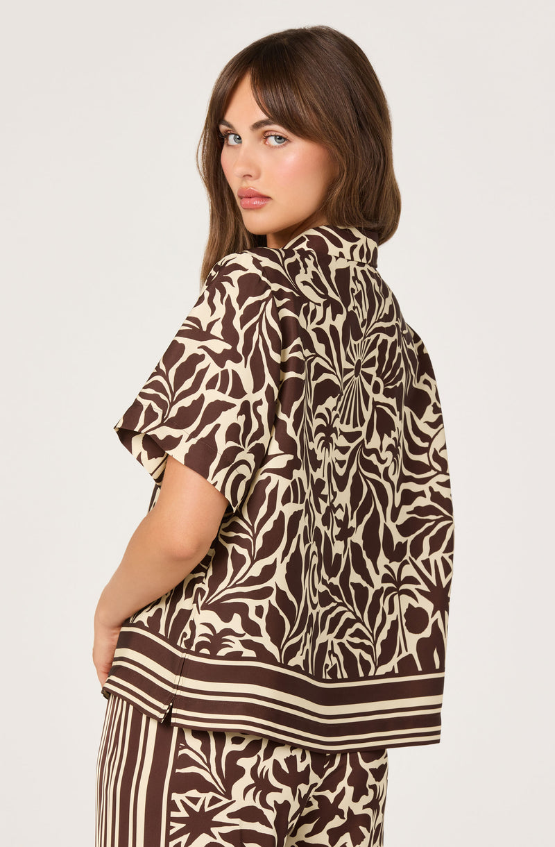 Woman in a brown and beige patterned short-sleeve shirt with bold, abstract designs.