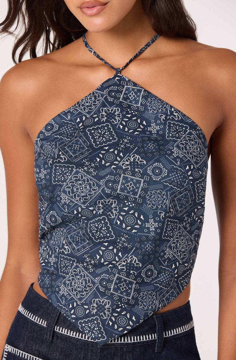 Woman wearing a halter top with a blue and white floral and geometric pattern.