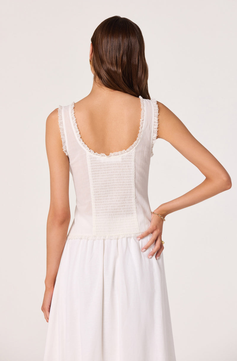 Woman wearing a sleeveless white dress with lace details on the straps and back.