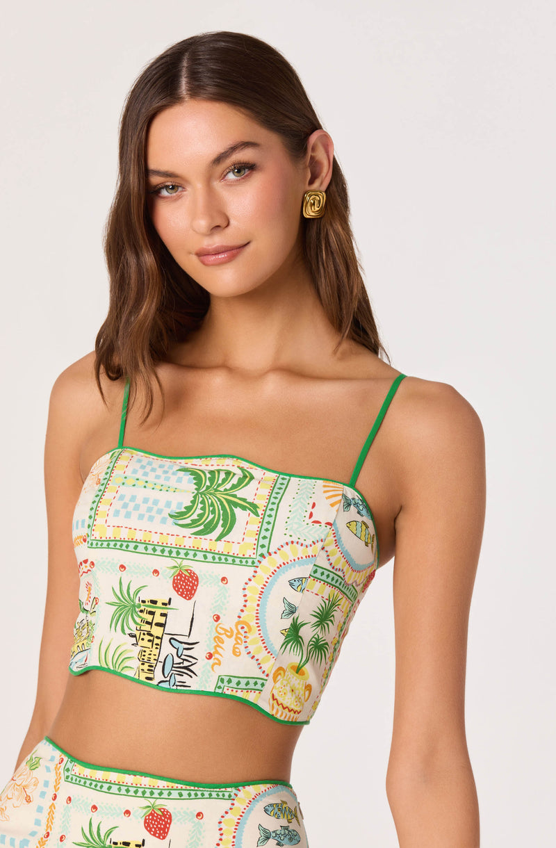 Woman wearing a colorful, patterned crop top with green spaghetti straps.