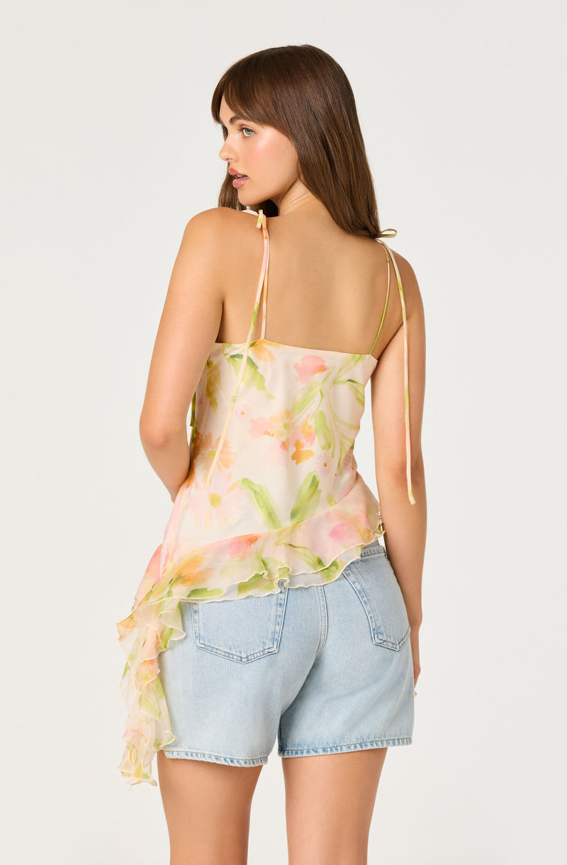 Woman wearing a pastel floral sleeveless top with ruffle detail and light-wash denim shorts.