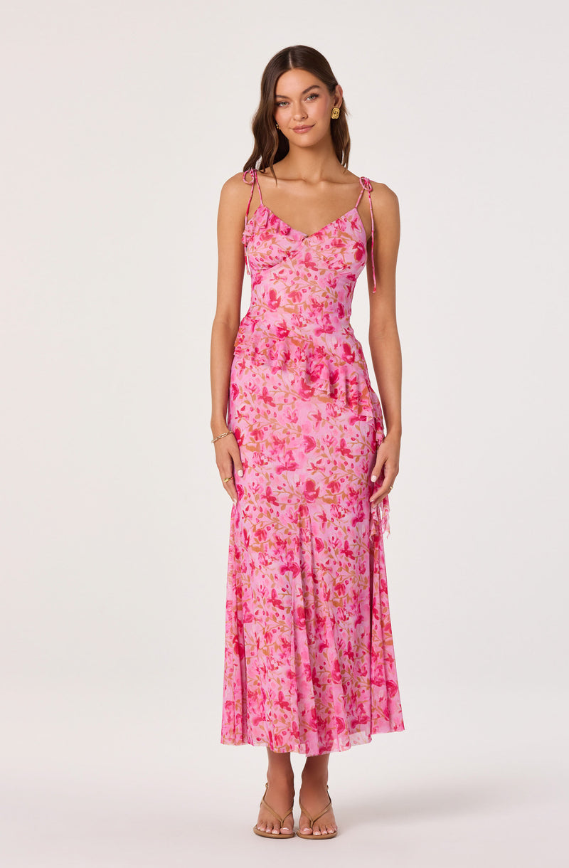 Woman wearing a pink floral tie-strap maxi dress with ruffle details.
