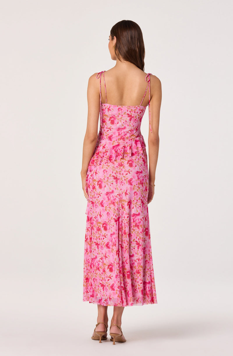 Back view of a woman wearing a pink floral maxi dress with spaghetti straps.