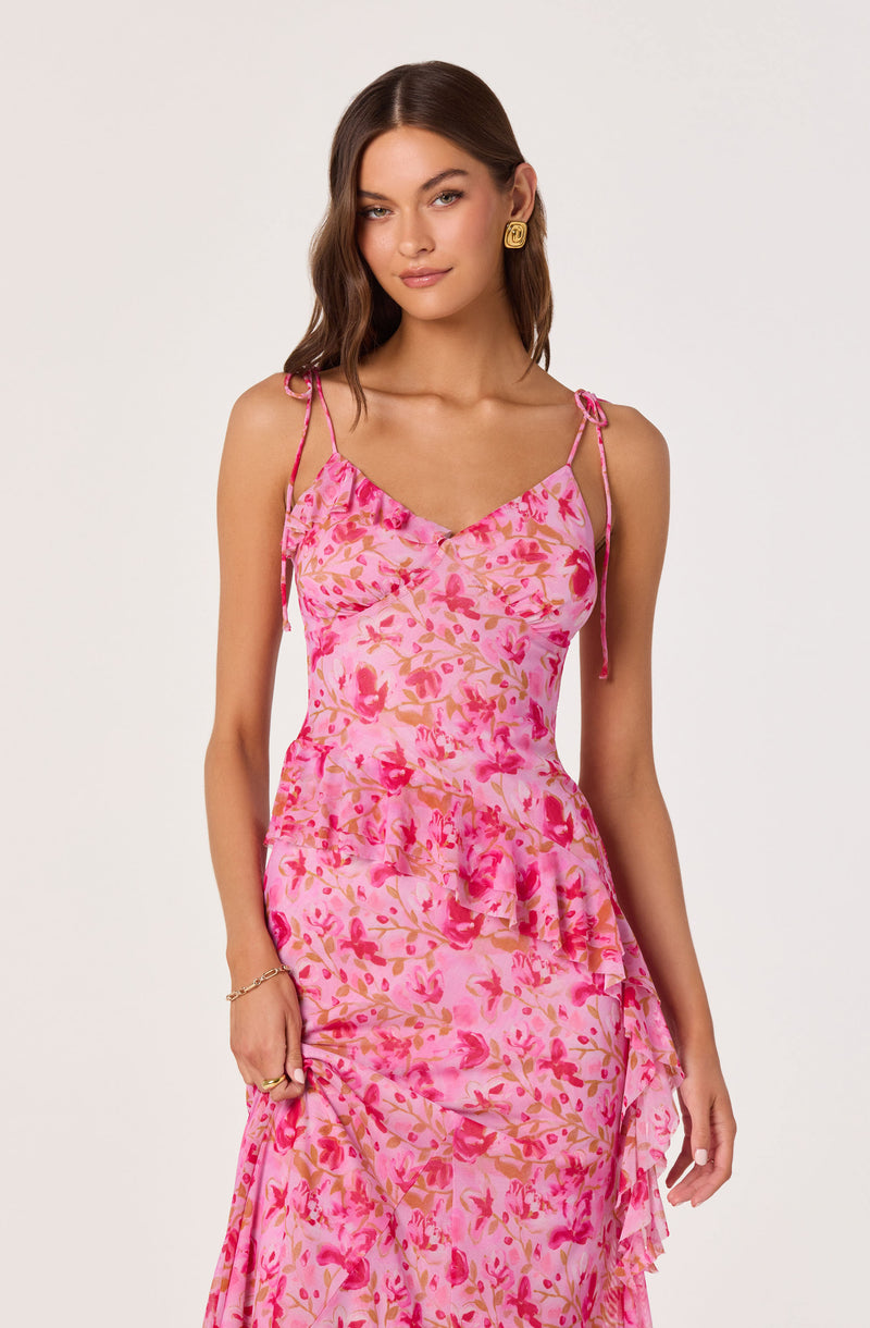 Woman wearing a pink floral dress with spaghetti straps and ruffles.