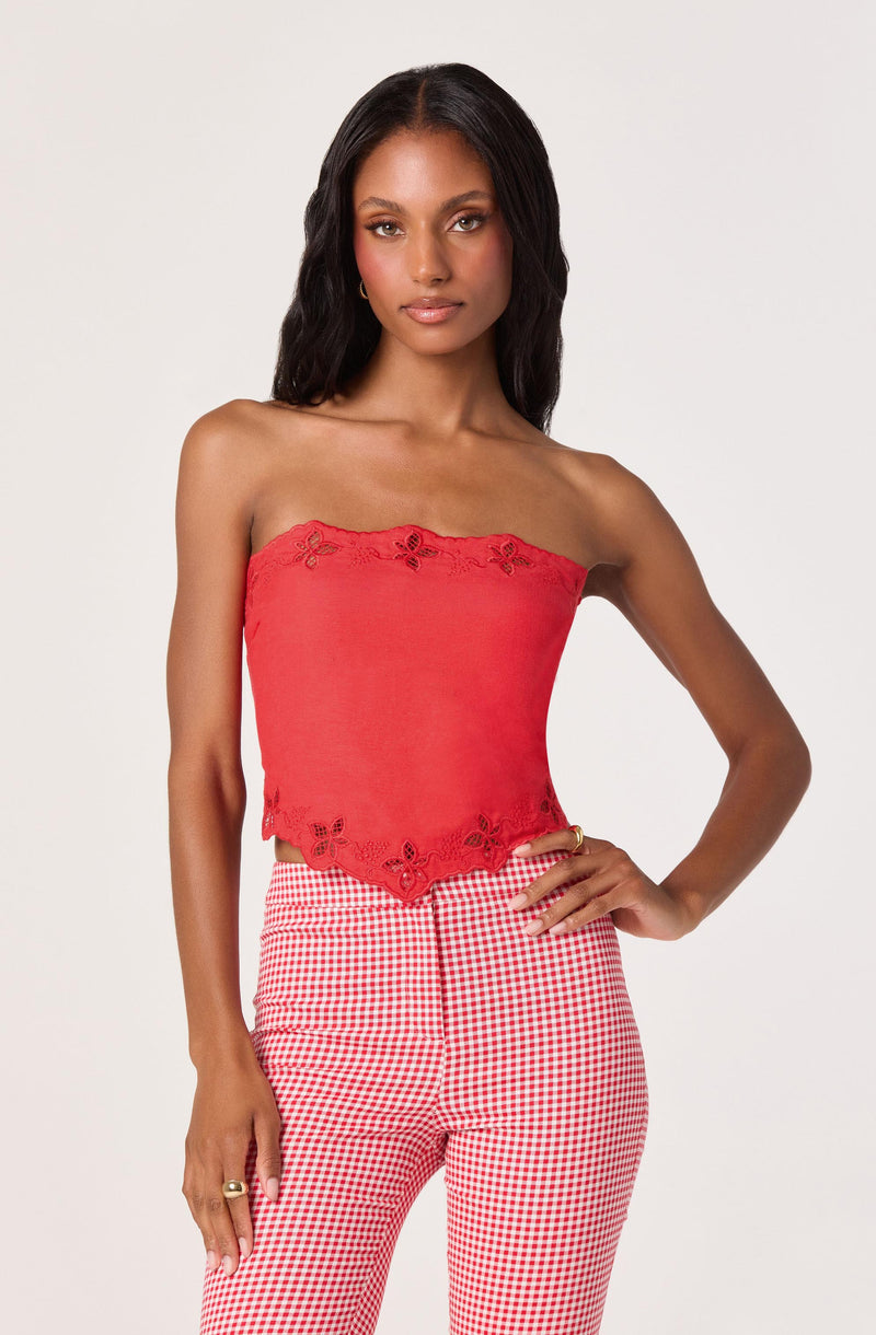 Woman in a red strapless top with lace and butterfly details, paired with red and white gingham pants.