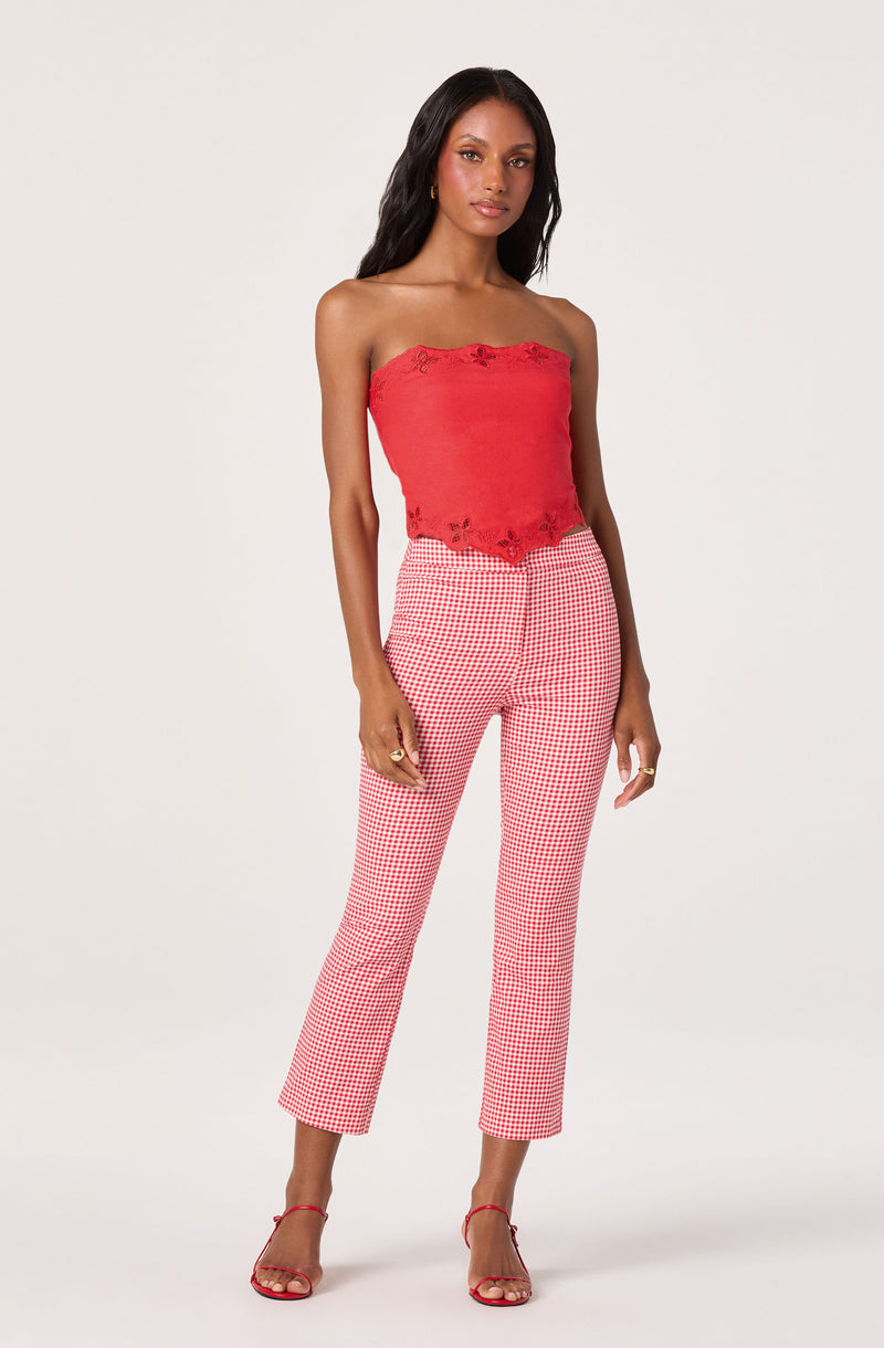 Woman in a red strapless crop top with crochet details and red-and-white checkered pants.