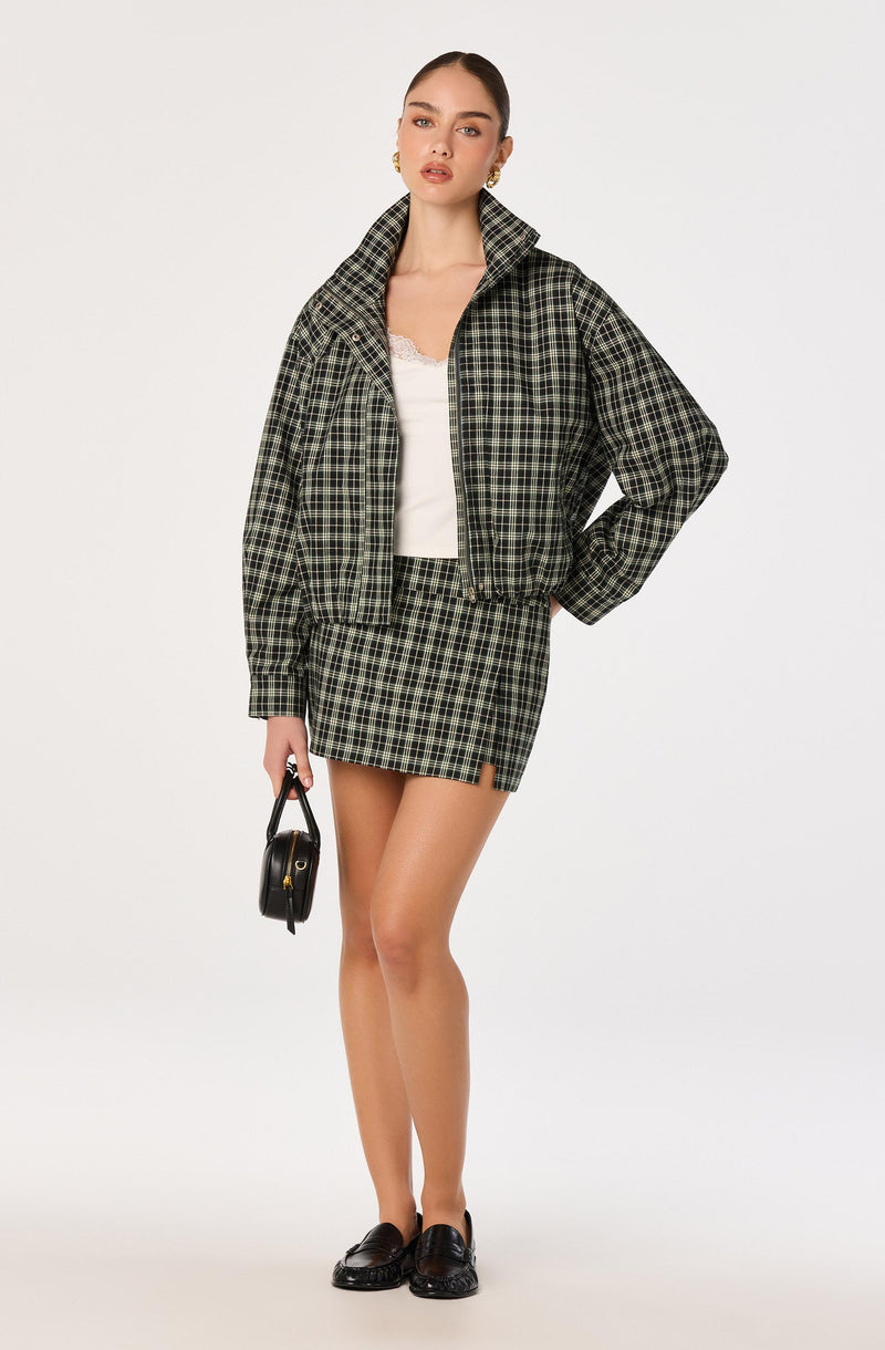 Woman wearing a green and black plaid jacket and matching skirt.
