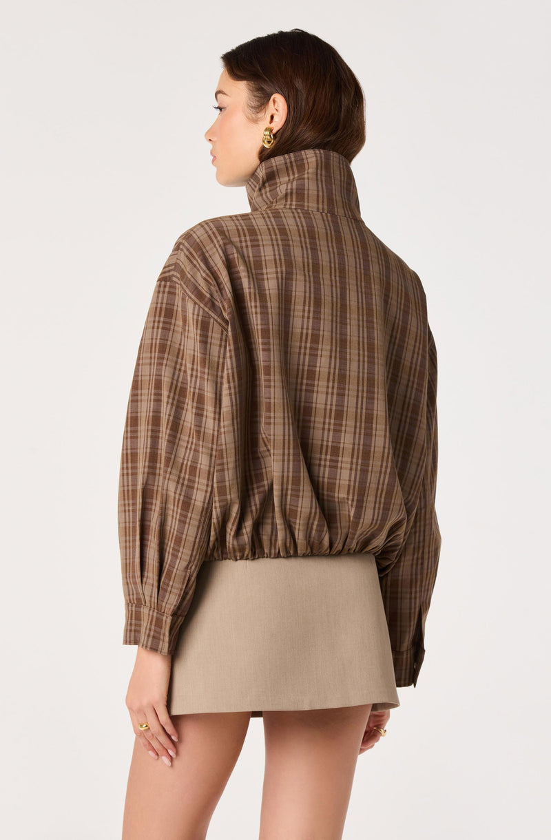 Woman wearing a brown plaid oversized turtleneck with puffed sleeves.