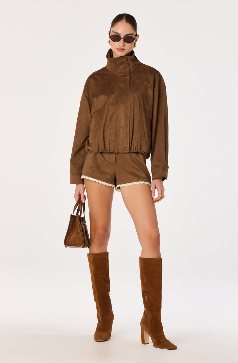 Woman wearing a brown jacket, matching shorts, and knee-high brown boots.