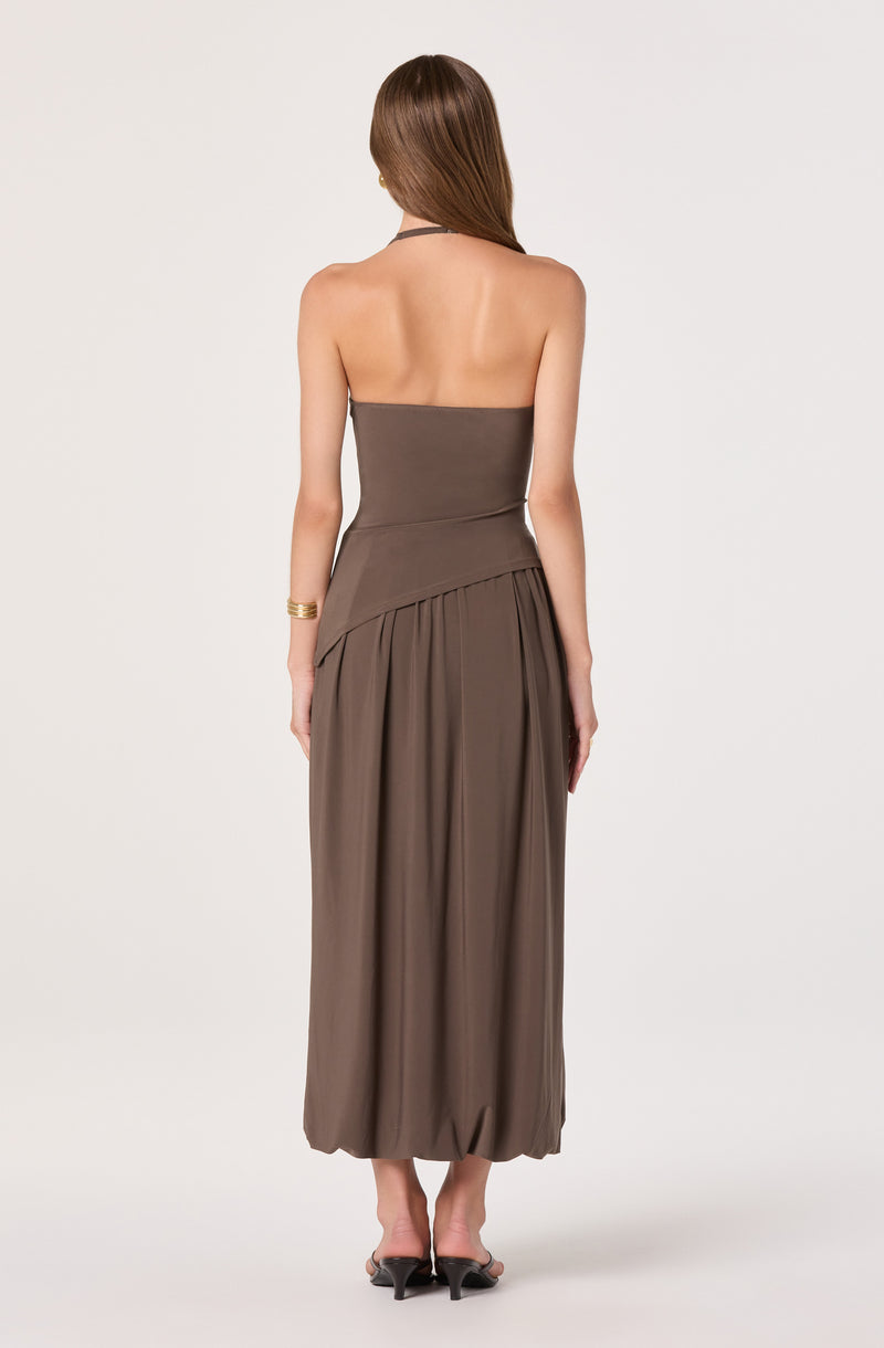 Back view of a woman wearing a strapless, taupe-colored, flowy maxi dress with a fitted bodice.