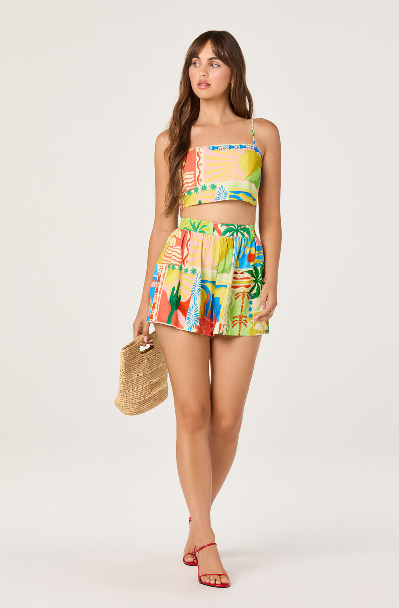 Young woman in a colorful, tropical-patterned two-piece outfit with a crop top and shorts.