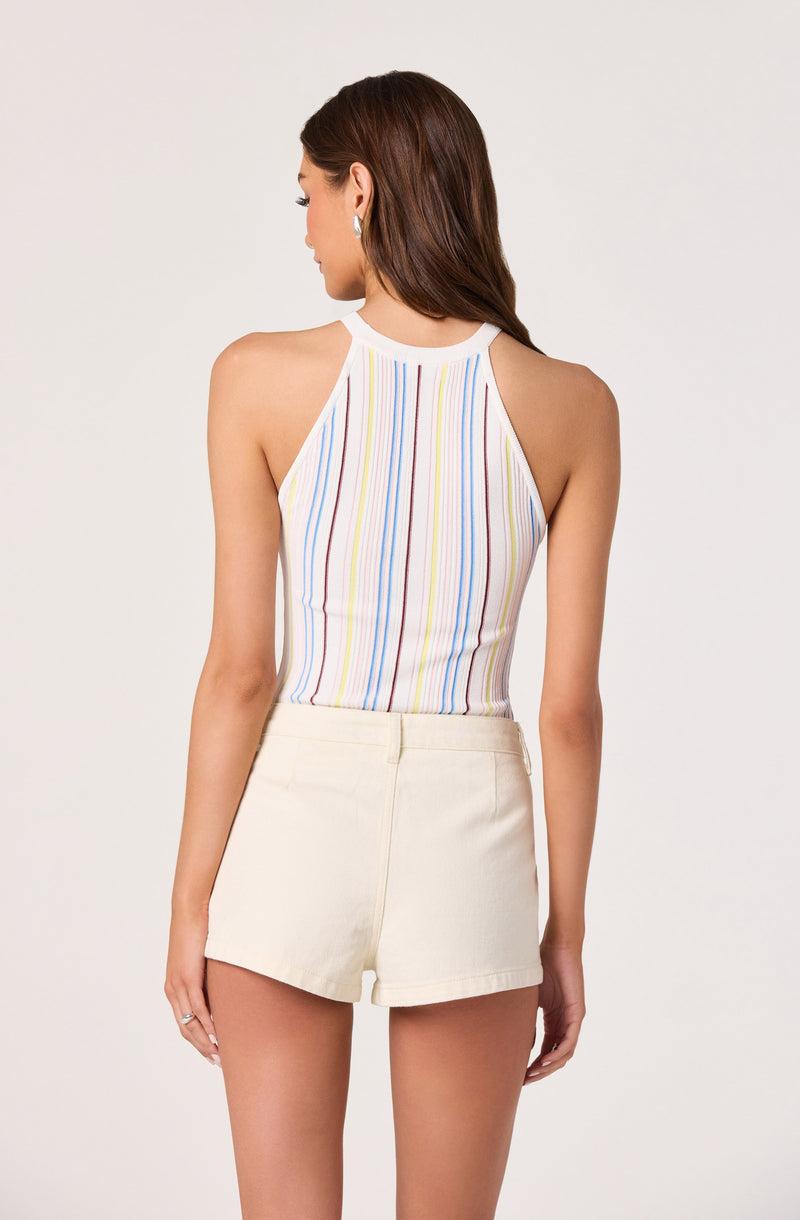 Woman wearing a multicolored striped sleeveless top and high-waisted light-colored shorts.