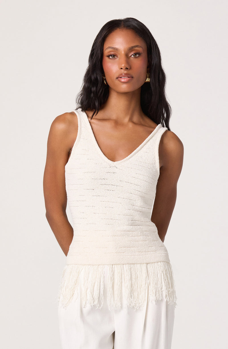 Woman wearing a sleeveless white tank top with textured horizontal stripes and fringe at the bottom.