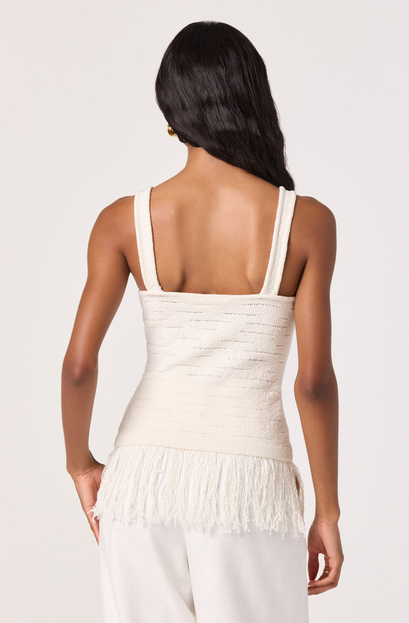 Back view of a woman wearing a cream-colored textured top with fringe details at the hem.