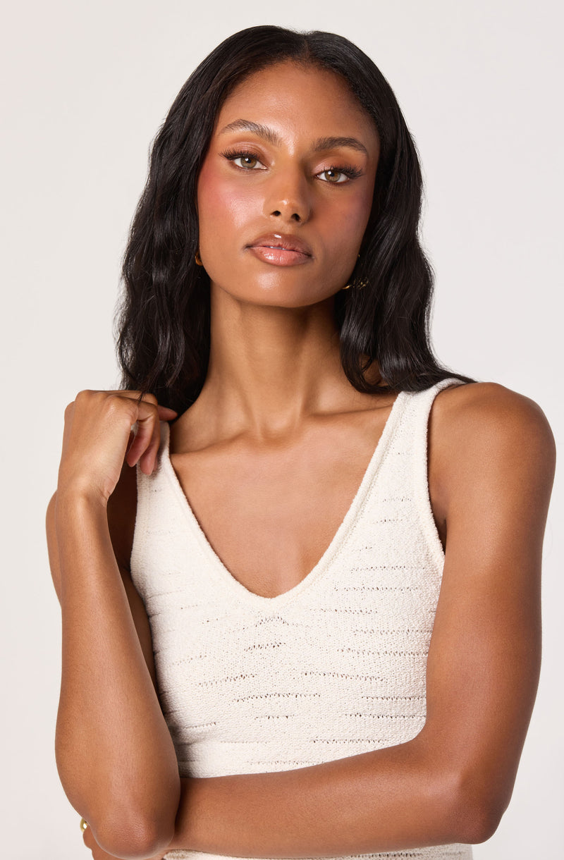 Woman in a sleeveless, cream-colored knit top with a V-neckline.