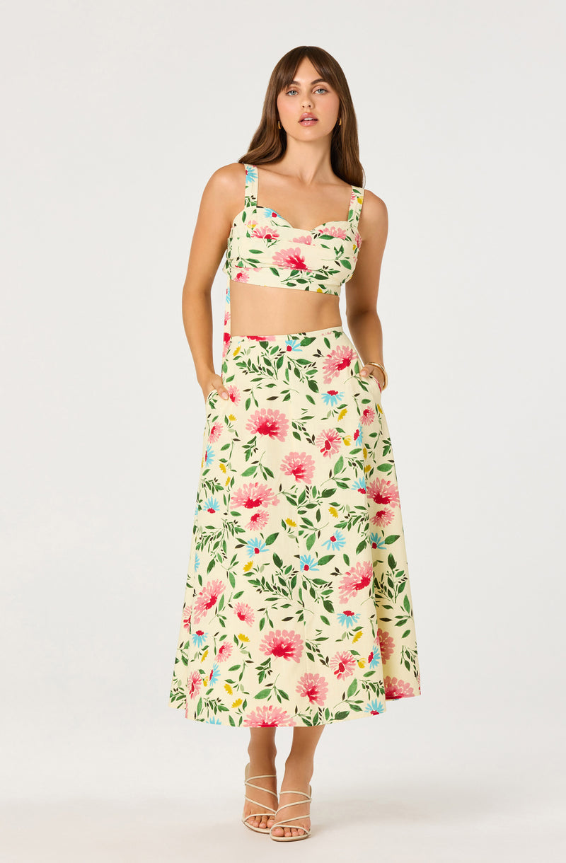 Woman wearing a matching floral crop top and wide-leg skirt in cream with pink, yellow, and green floral print.