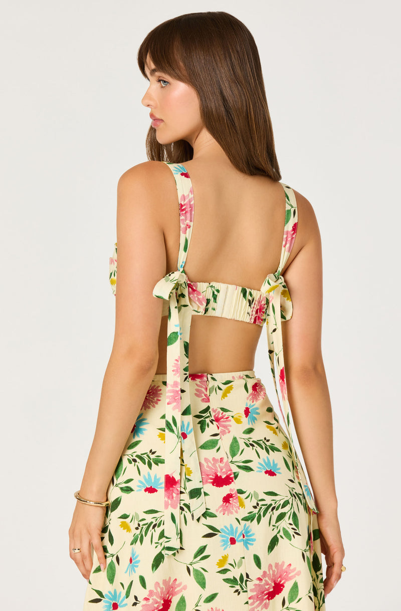 Woman in a floral sleeveless dress with ties on the shoulders and an open back.