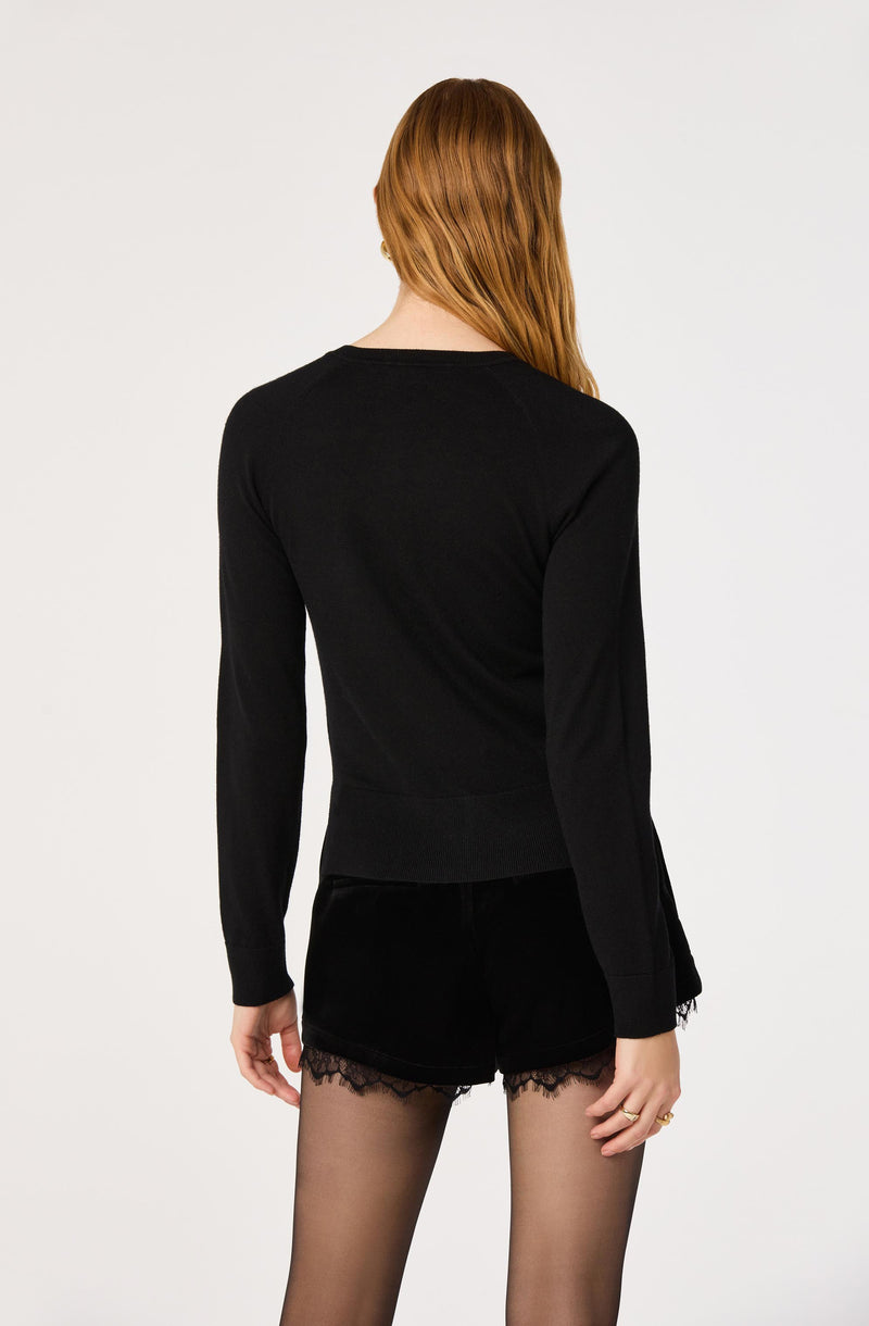 Woman wearing a black long-sleeve top and black shorts with lace trim, shown from behind.