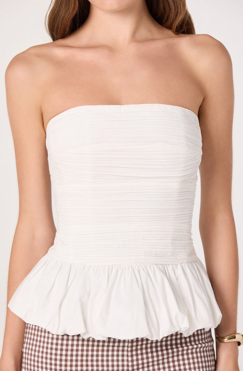 White strapless top with ruched bodice and ruffled hem, paired with checkered pants.