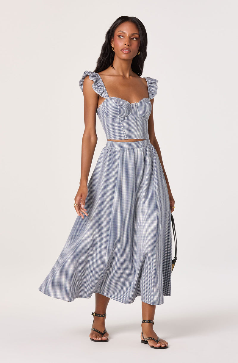 Woman wearing a two-piece blue and white gingham outfit with ruffled shoulder straps and a long, flowy skirt.