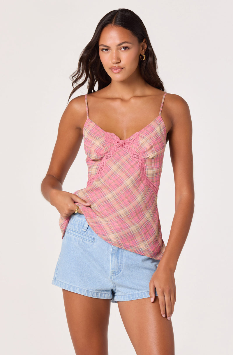 Woman wearing a pink plaid spaghetti strap top and light blue denim shorts.