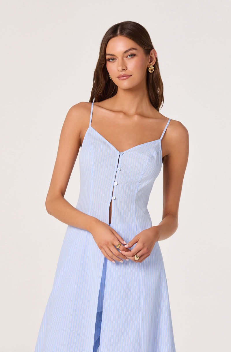 Woman wearing a light blue and white striped sleeveless dress with thin straps, buttoned front, and split skirt.