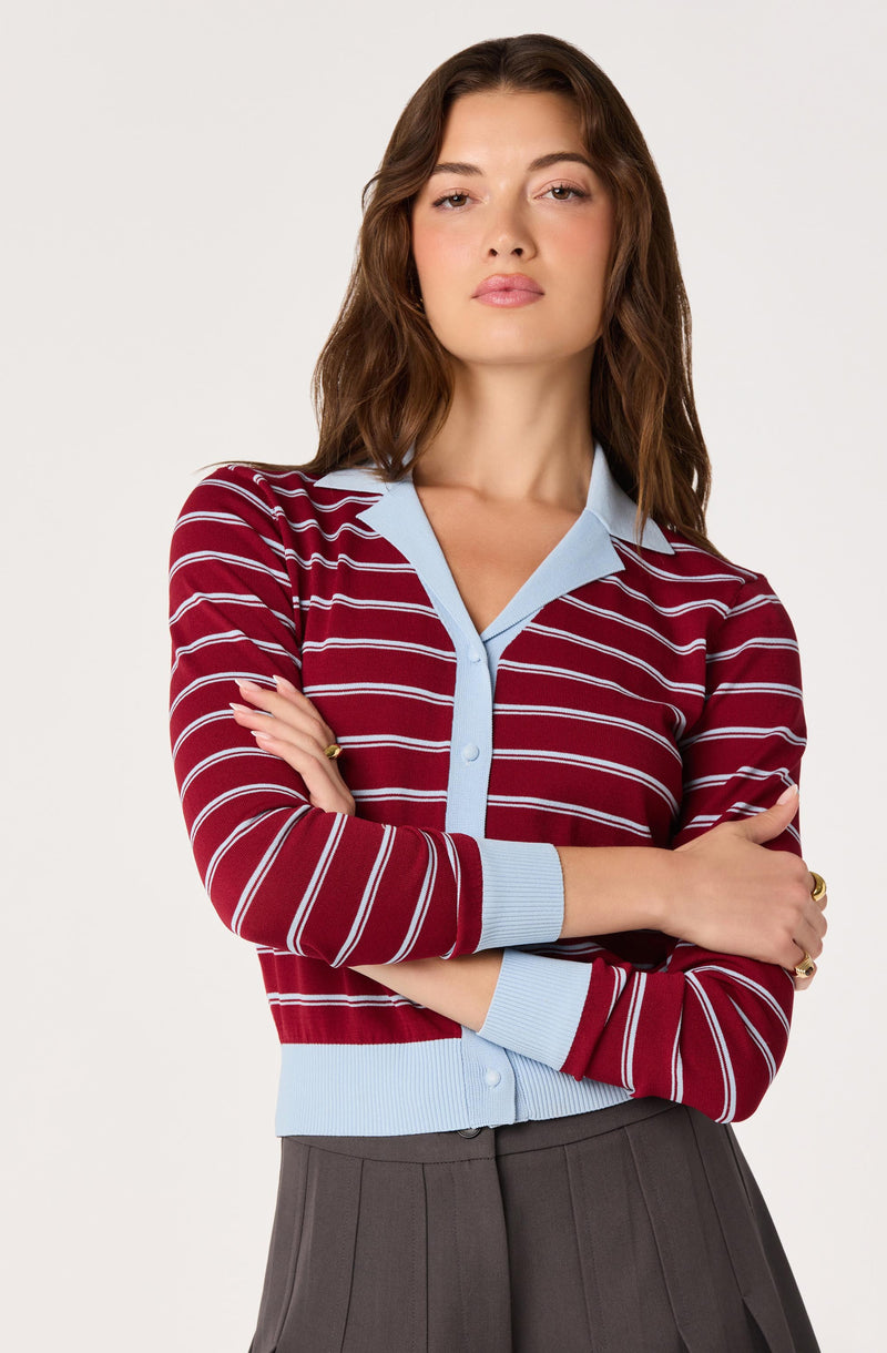 Woman wearing a red and white striped cardigan with light blue trim and buttons, paired with gray pants.