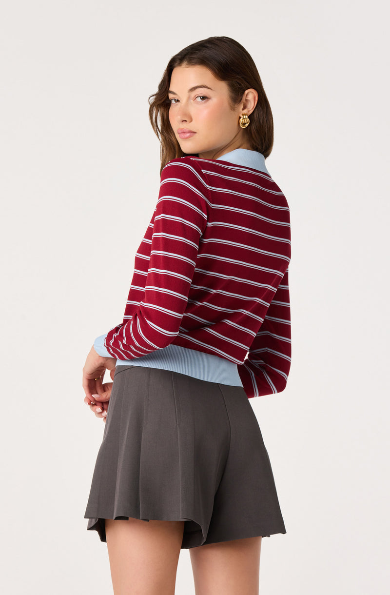 Woman wearing a red and white striped sweater with a light blue collar, gray pleated shorts.