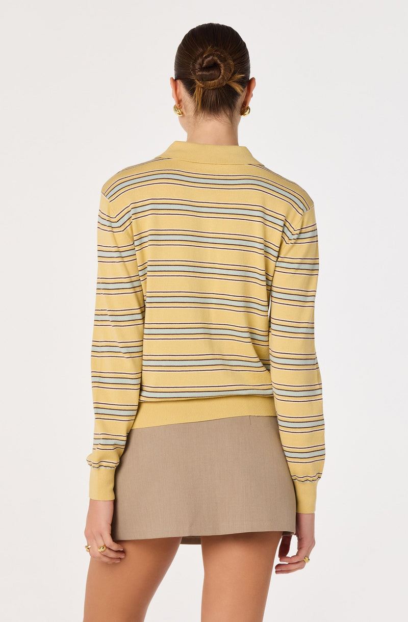 Woman wearing a yellow striped long-sleeve top and beige mini skirt, view from the back.