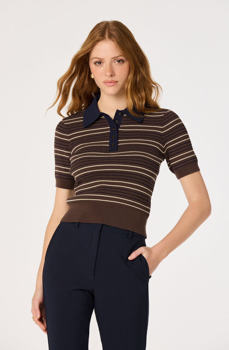 Striped short-sleeve sweater with a navy collar and buttons, tucked into navy trousers.