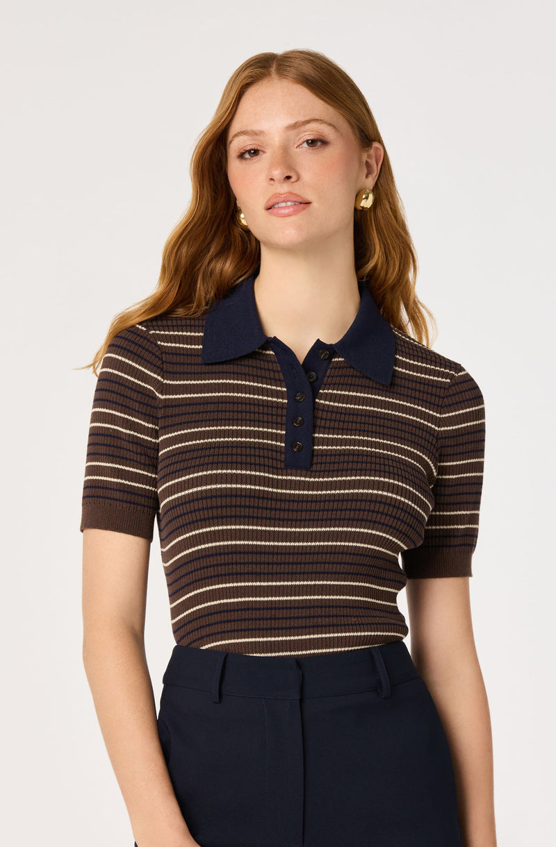 Woman wearing a brown, beige, and navy striped short-sleeve polo shirt with a navy collar.
