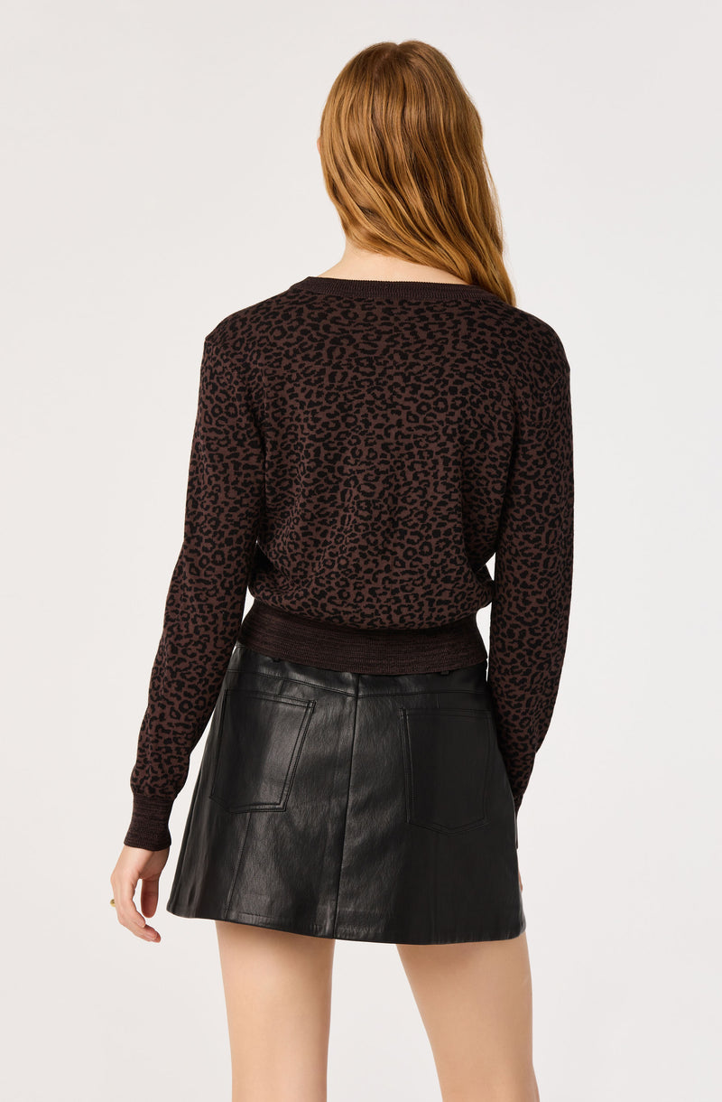 Woman wearing a black leopard-print sweater and a black leather skirt.